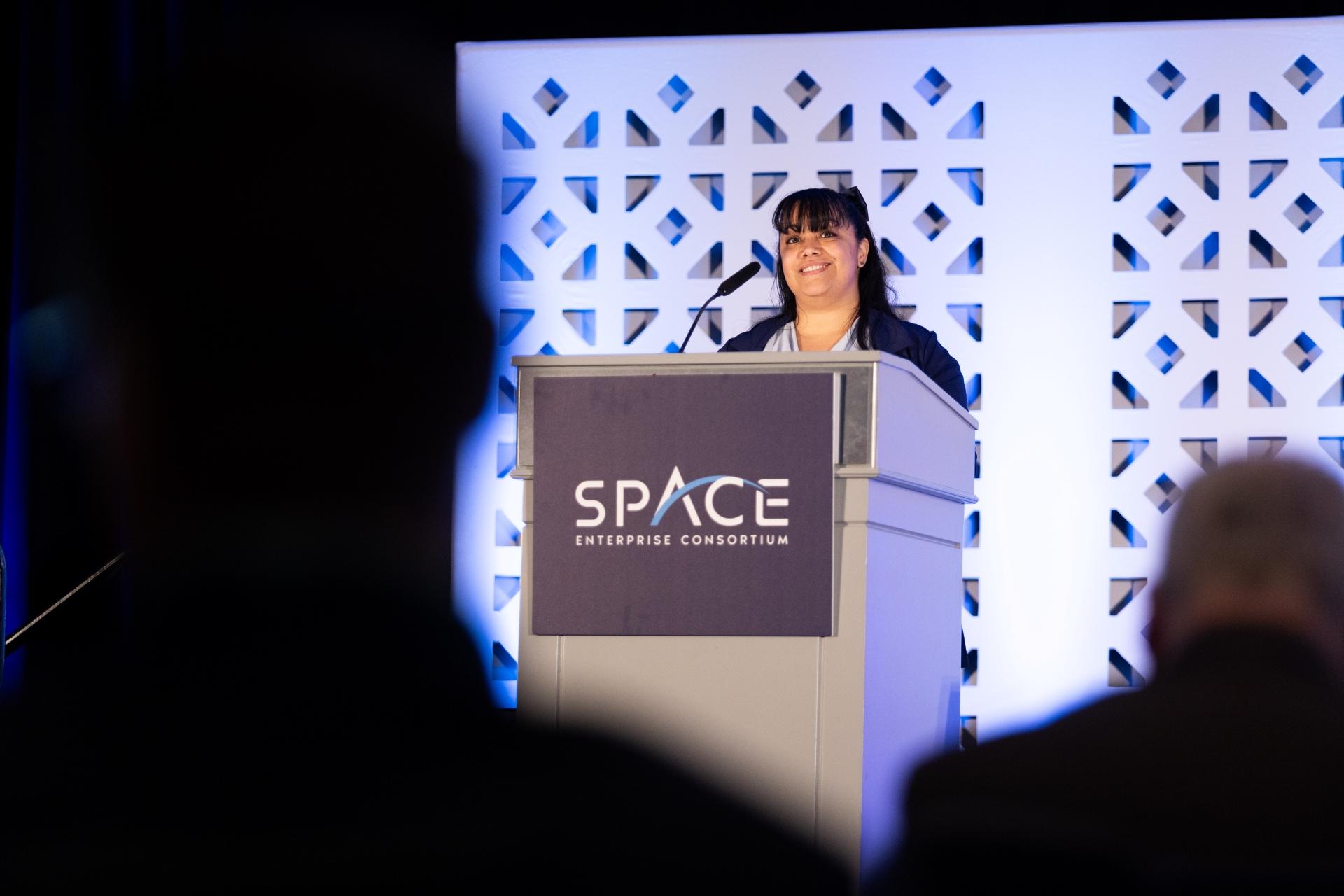 Speaker speaking on main stage at SpEC GMM